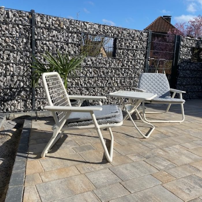 Gabionenwand als Sichtschutz hinter einer gepflasterten Terrasse