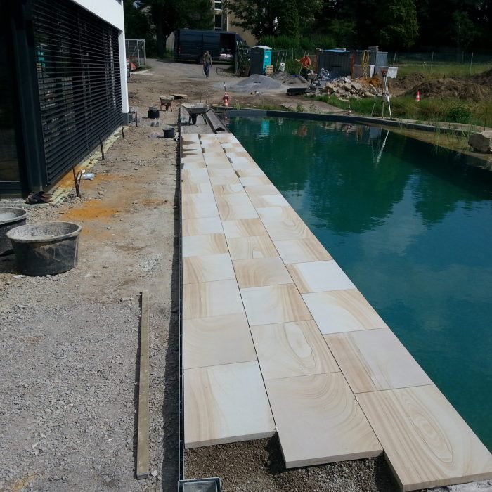 Poolrand aus hellen Sandsteinplatten während der Bauphase