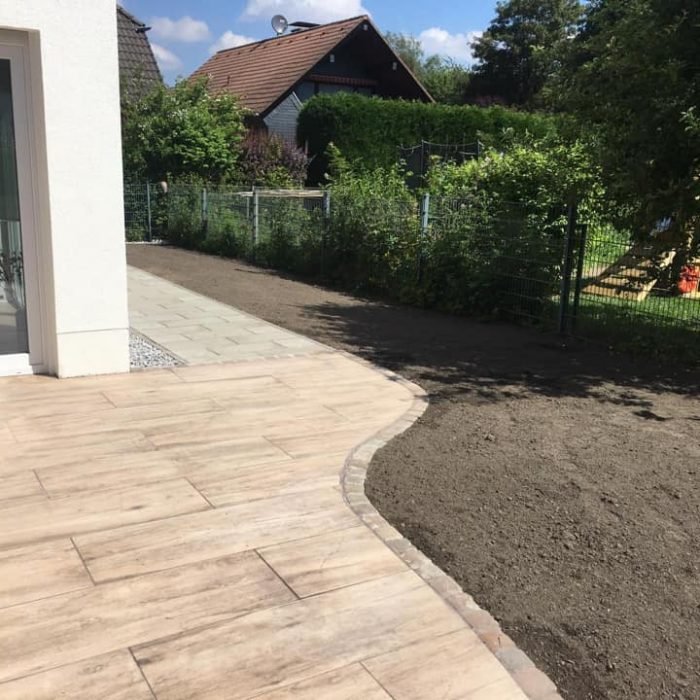 Terrasse aus Feinsteinzeug in Holzoptik mit geschwungener Pflasterkante
