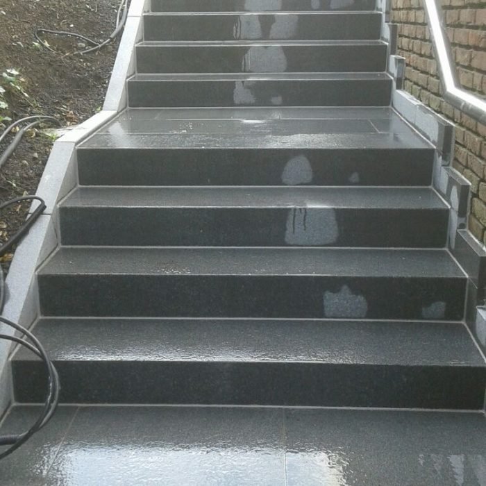 Außentreppe mit dunklen Granitstufen entlang einer Klinkerwand